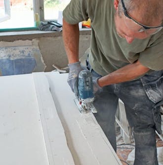 Ny gipsloft med synlige bjælker: Sav gipspladen til efter skabelonens form Ny gipsloft med synlige bjælker: Sav gipspladen til efter skabelonens form